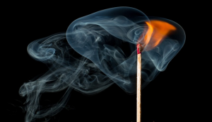 A lit match against a black background, symbolizing fire prevention measures for businesses.
